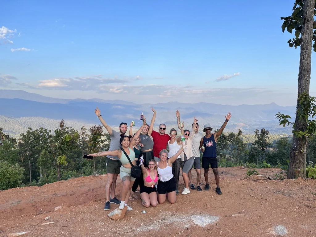 A tour group cheering at a mountain viewpoint above the valley
