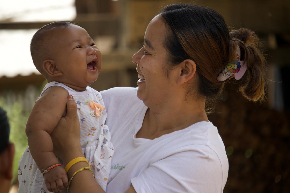 A mother laughing with her baby in her arms