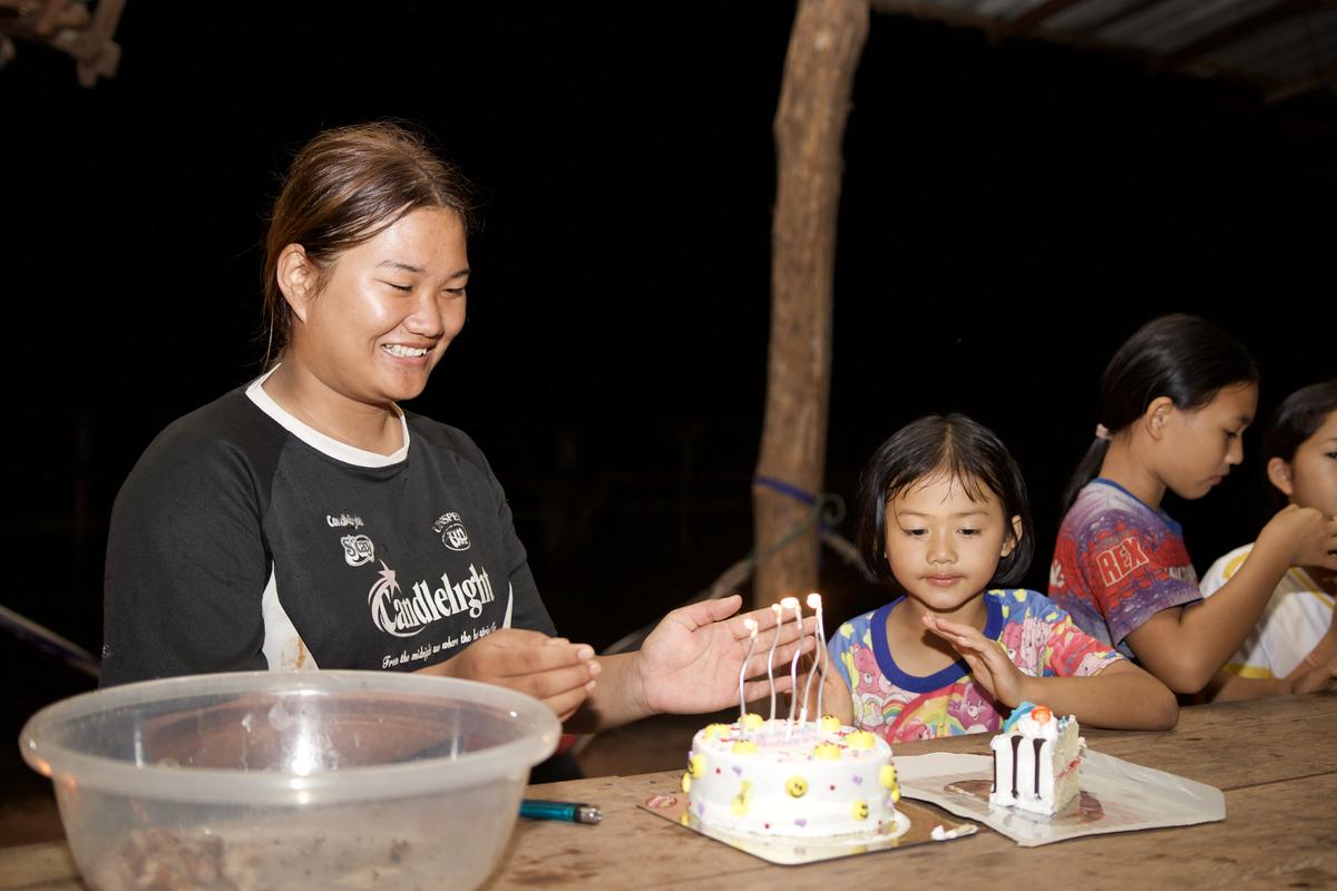 Children gathered around a birthday cake at night