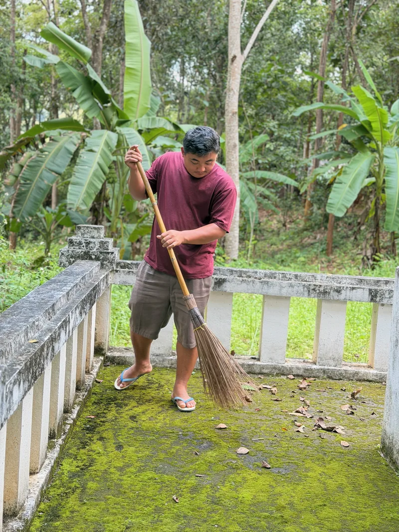 A man sweeping a shaded path in the village