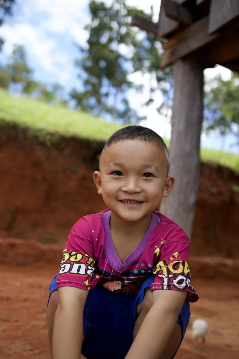 A beaming village boy outdoors in the daylight